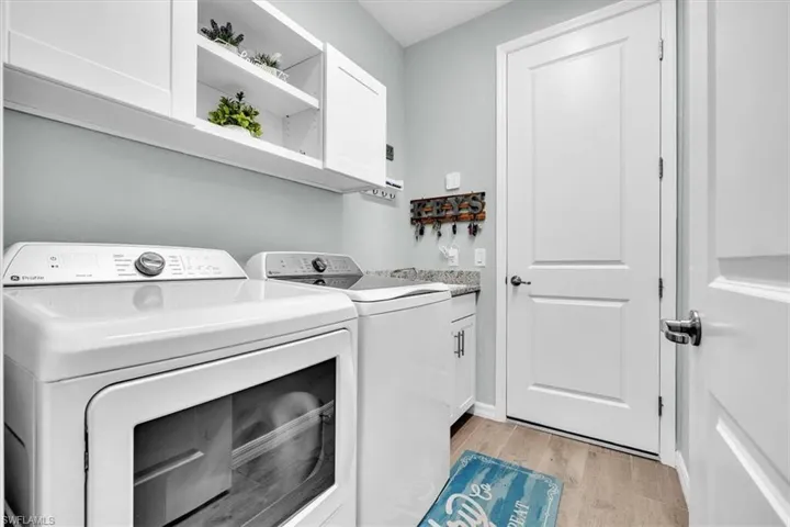 White cabinetry with open shelving, granite-style countertop, and wood-finish flooring