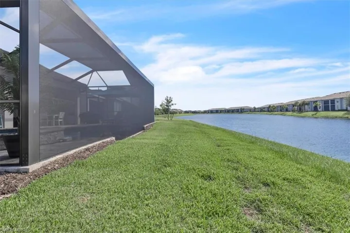 Screened outdoor enclosure with a concrete foundation and a grassy area along a canal