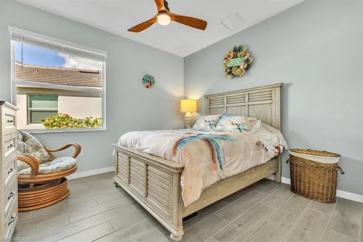 Wood-look tile flooring throughout, featuring a window with integrated blinds, and a ceiling fan with light fixture