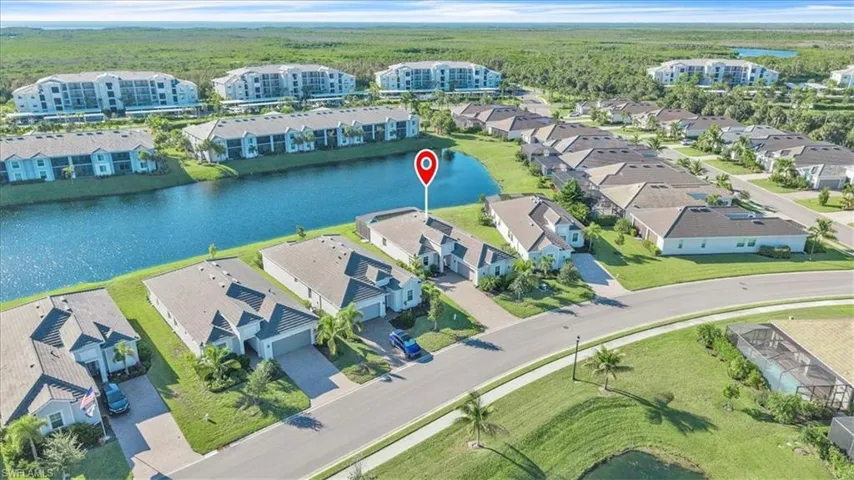 Waterfront property with a paver driveway, attached garage, and lush green landscaping