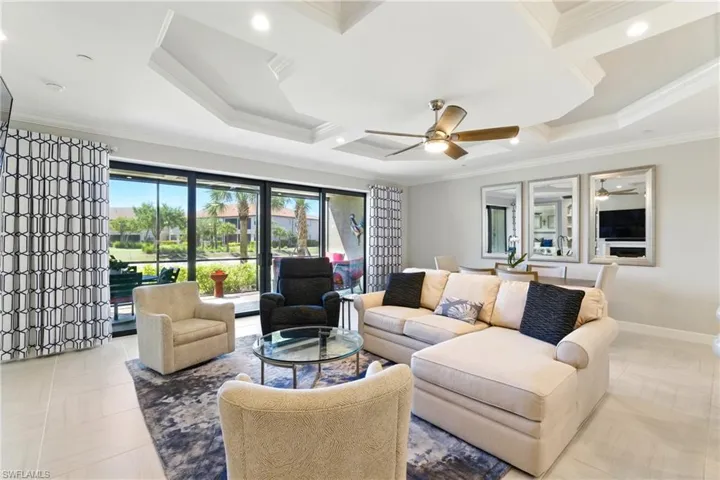 Living area with crown molding, baseboards, coffered ceiling, and ceiling fan