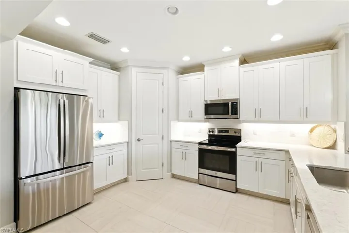 Kitchen with white cabinets, visible vents, backsplash, and appliances with stainless steel finishes