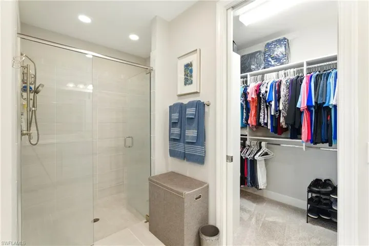Full bath featuring baseboards, a stall shower, and a spacious closet