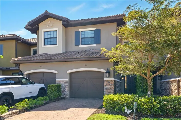 View of front of home featuring stone siding, stucco siding, a tiled roof, decorative driveway, and a garage
