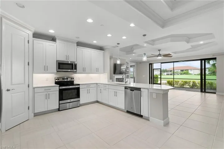 Kitchen featuring appliances with stainless steel finishes, ornamental molding, a peninsula, a sink, and open floor plan