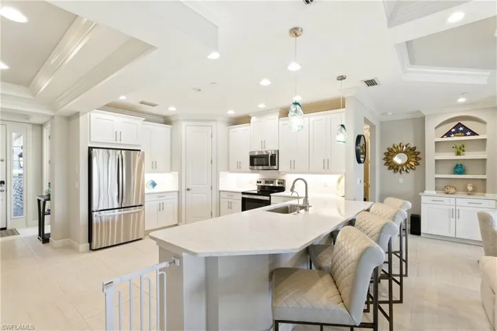 Kitchen featuring crown molding, stainless steel appliances, a breakfast bar, a sink, and visible vents