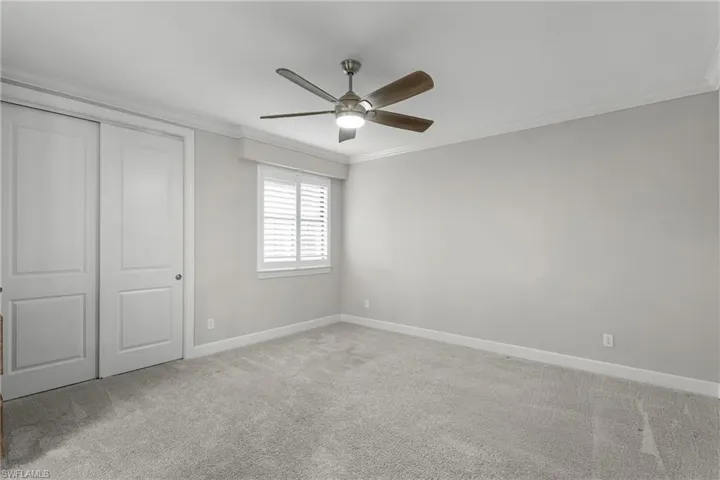 Unfurnished bedroom featuring ornamental molding, carpet flooring, baseboards, a closet, and ceiling fan