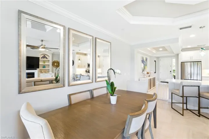 Dining space with ornamental molding, built in shelves, a raised ceiling, visible vents, and a ceiling fan