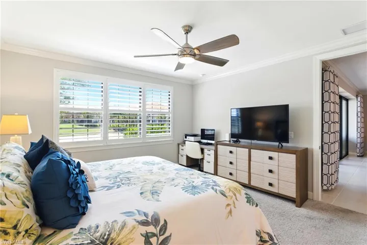 Carpeted bedroom featuring a ceiling fan, crown molding, and visible vents