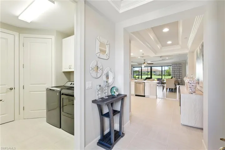Hallway featuring a tray ceiling, crown molding, washing machine and clothes dryer, and recessed lighting