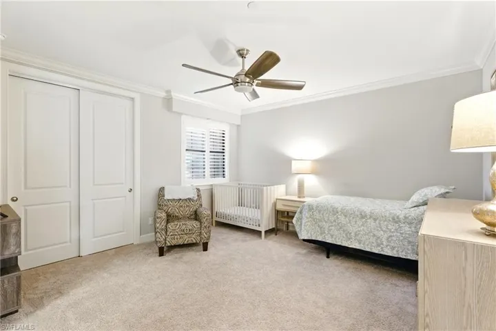 Bedroom featuring a closet, carpet floors, ornamental molding, and a ceiling fan