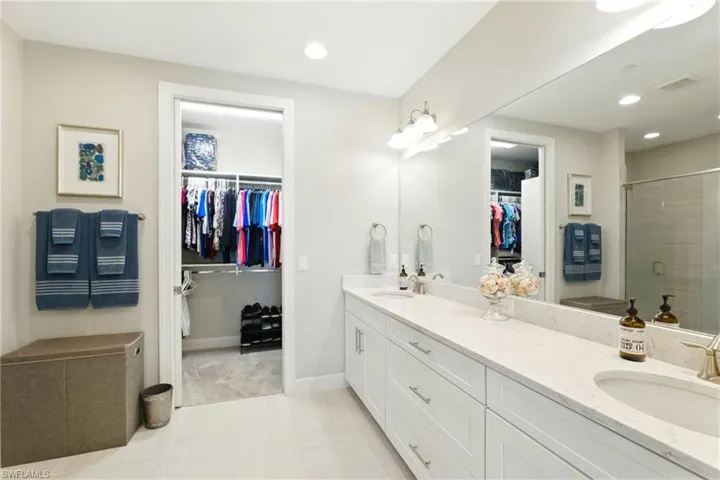 Bathroom featuring double vanity, a sink, a stall shower, and a spacious closet