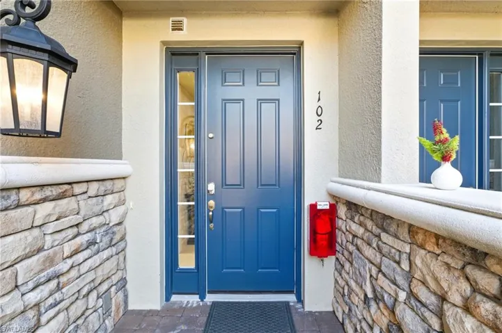 View of exterior entry featuring stone siding, stucco siding, and visible vents