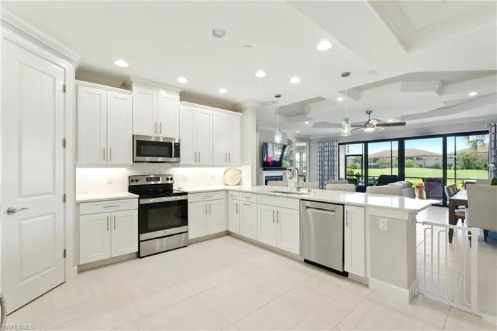 Kitchen featuring light countertops, a sink, appliances with stainless steel finishes, a peninsula, and open floor plan