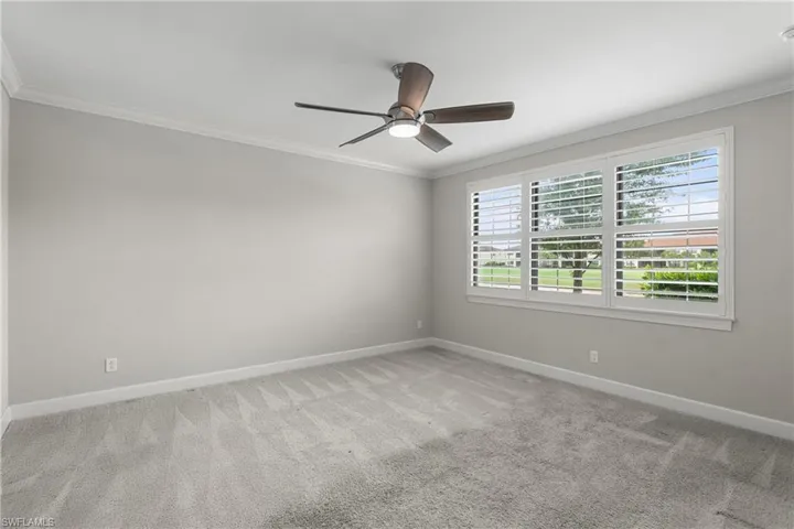 Carpeted spare room with crown molding, baseboards, and ceiling fan