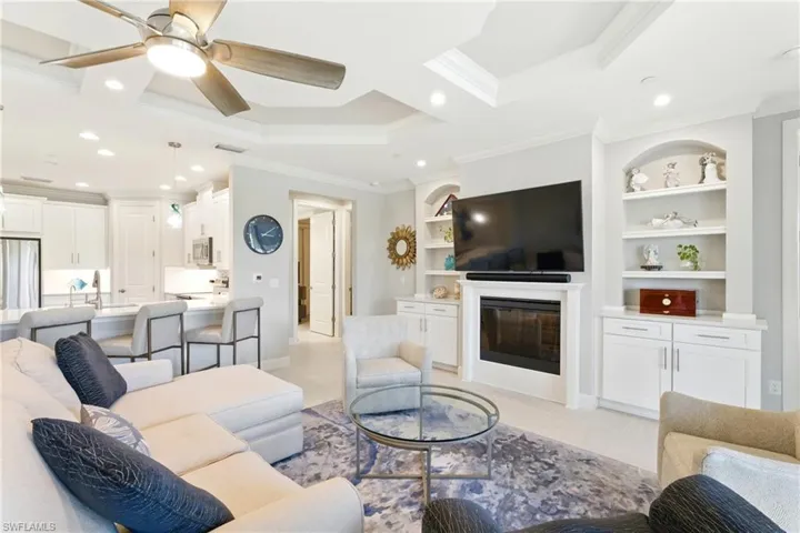 Living area featuring ornamental molding, a glass covered fireplace, recessed lighting, and a ceiling fan