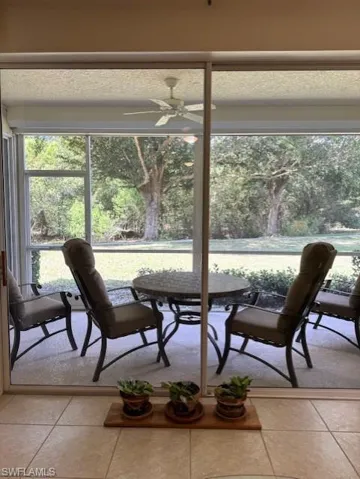 Dining area featuring ceiling fan, light tile patterned flooring, and view of scattered trees