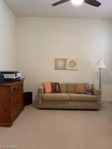 Living room with a ceiling fan and light colored carpet