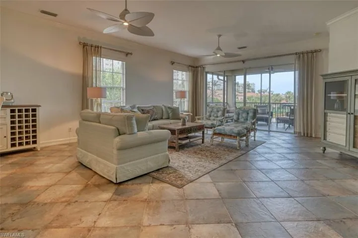 Living room featuring ceiling fan, a wealth of natural light, and ornamental molding