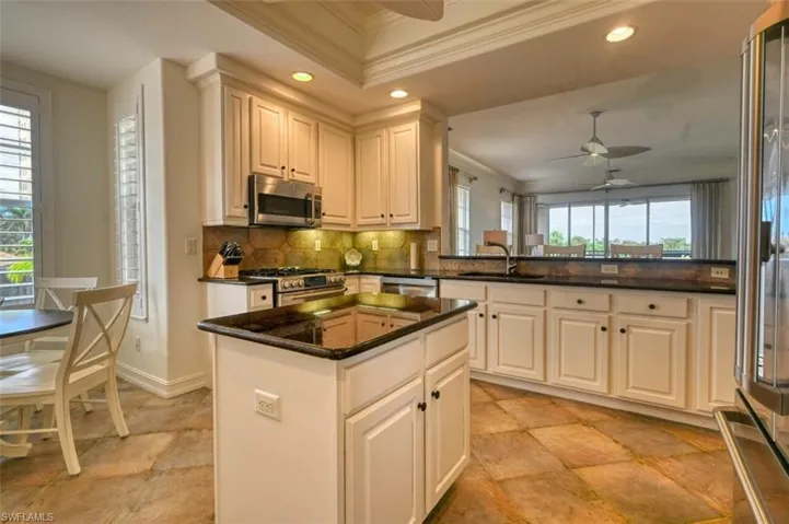 Kitchen featuring a wealth of natural light, appliances with stainless steel finishes, crown molding, and white cabinets