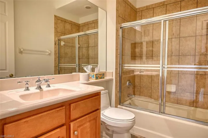 Full bathroom featuring combined bath / shower with glass door, vanity, and toilet