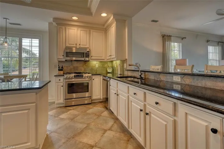 Kitchen featuring pendant lighting, stainless steel appliances, dark stone countertops, sink, and ornamental molding