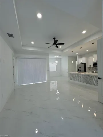 Unfurnished living room with ceiling fan and a raised ceiling