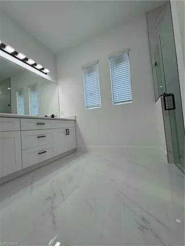 Bathroom featuring vanity, an enclosed shower, and a healthy amount of sunlight