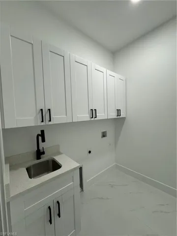 Laundry area with cabinets, hookup for a washing machine, electric dryer hookup, and sink