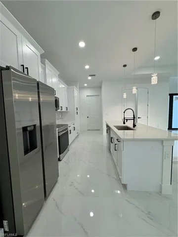 Kitchen featuring stove, white cabinetry, fridge, and sink