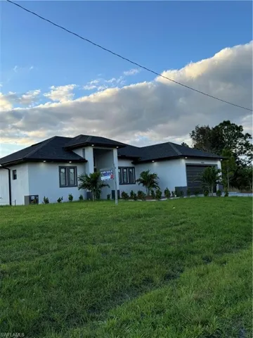 View of front of home with a garage, a front lawn, and cooling unit