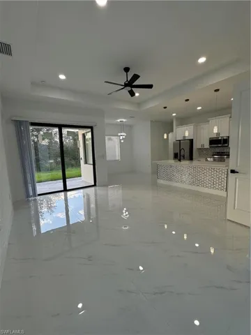 Unfurnished living room featuring ceiling fan and a raised ceiling