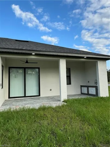 Rear view of property featuring ceiling fan, a yard, and a patio