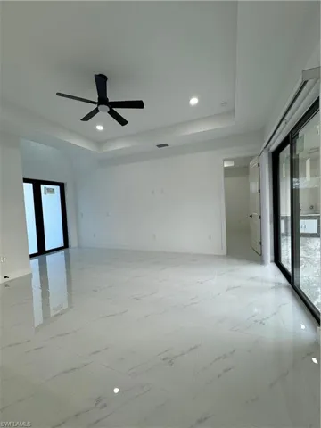 Empty room featuring ceiling fan, a raised ceiling, and french doors
