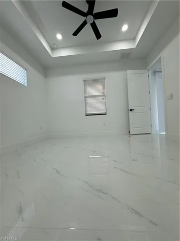 Empty room featuring ceiling fan and a raised ceiling