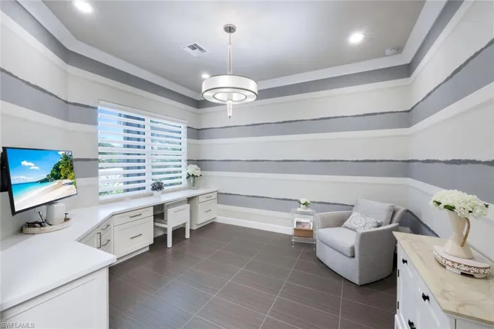 This den features a great built-in desk with ample storage, designer light fixture, recessed lighting, and Hunter Douglas wide pleated electric shades.