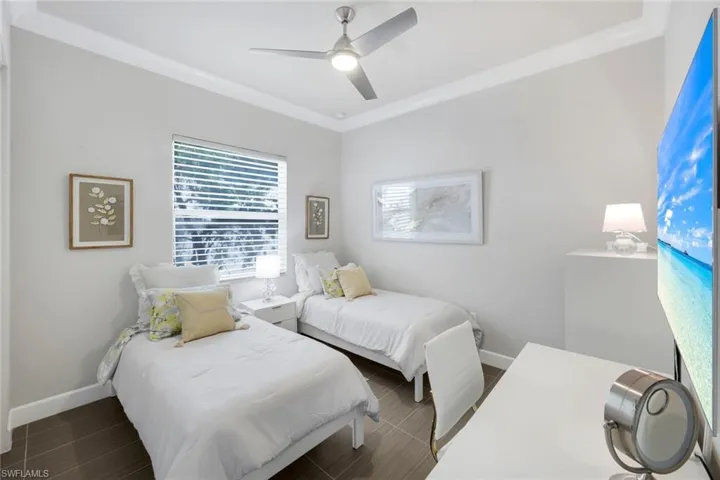 Spacious Guest bedroom with ceiling fan + light, crown molding, and Hunter Douglas window treatments.