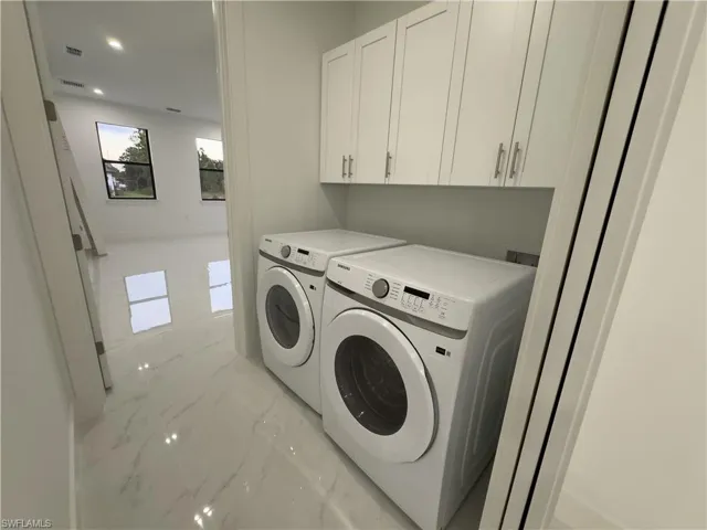 Washroom featuring light marble finish flooring, cabinet space, separate washer and dryer, and recessed lighting