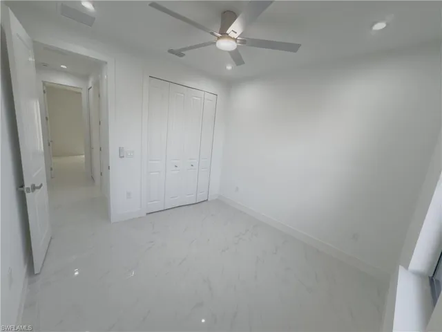 Unfurnished bedroom with recessed lighting, light marble finish flooring, a closet, and a ceiling fan
