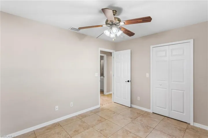 Unfurnished bedroom featuring a ceiling fan, a closet, and light tile patterned floors