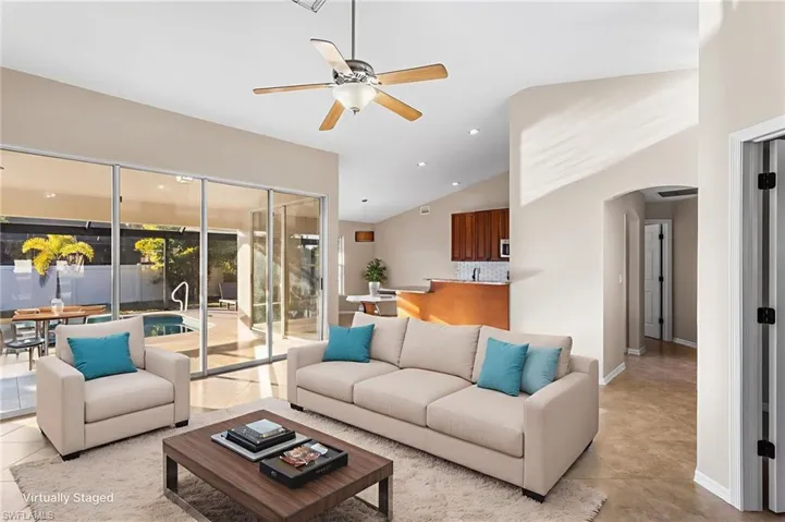 Virtually Staged Living room featuring arched walkways, a ceiling fan, recessed lighting, light tile patterned floors, and vaulted ceiling.