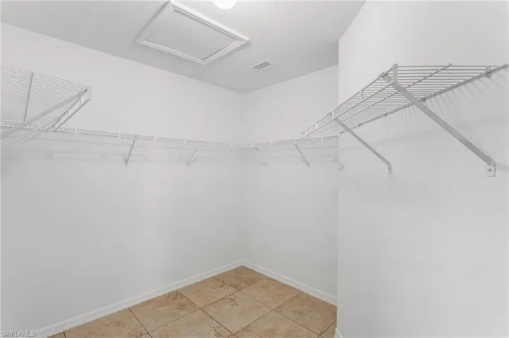 Walk in closet featuring attic access and light tile patterned floors