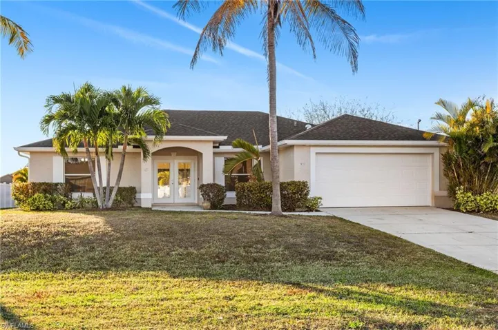 Single story home with french doors, stucco siding, a front lawn, driveway, and an attached garage.