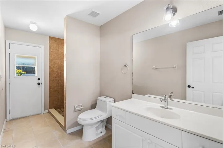 Full bath with walk in shower, vanity, and light tile patterned floors