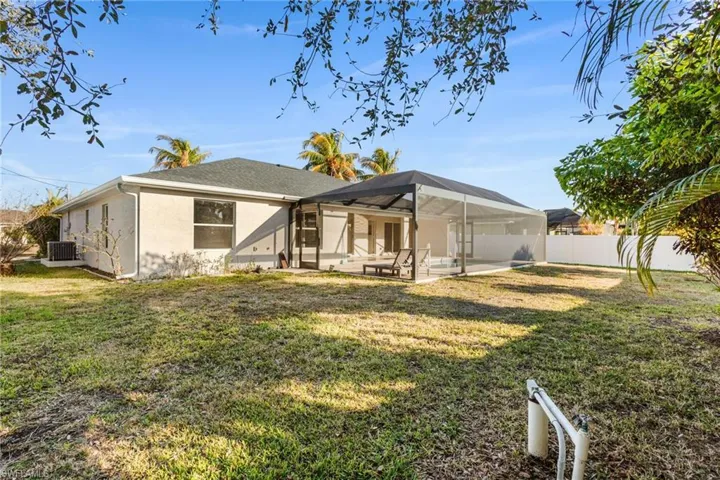 Back of property with a picture window screen cage, stucco siding, a lanai, a patio, and a fenced backyard