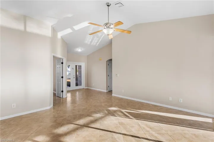 View of entry with lofted ceiling, a ceiling fan, and light tile floors.