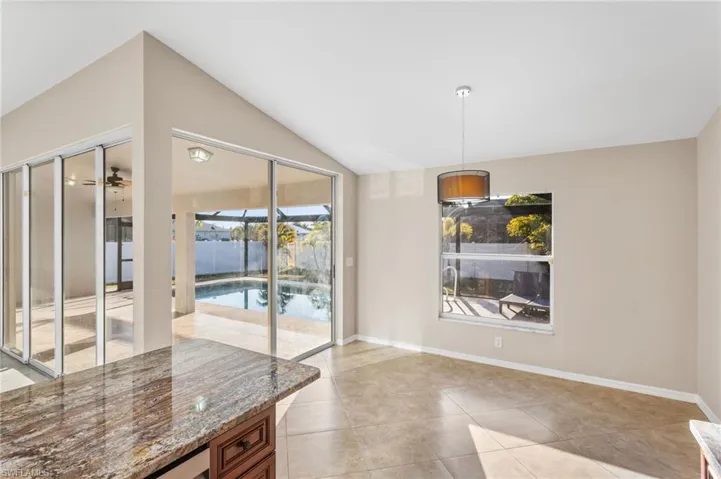 Unfurnished dining area with a sunroom, vaulted ceiling, a ceiling fan, and light tile patterned flooring
