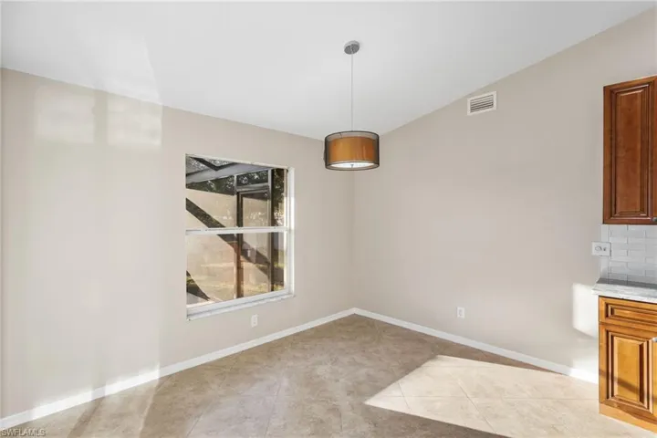 Unfurnished dining area featuring light tile patterned floors and vaulted ceiling
