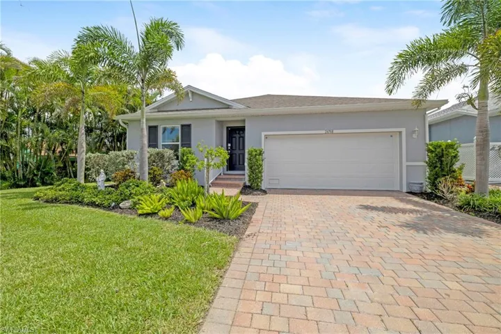 Ranch-style home with stucco siding, decorative driveway, a front lawn, and a garage