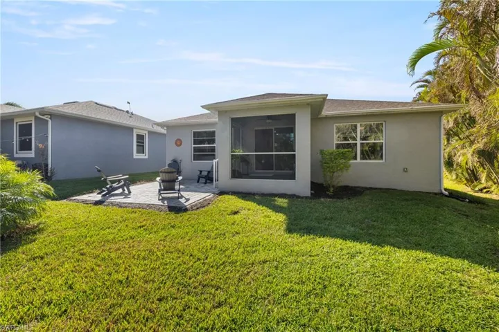 Back of property featuring stucco siding, a patio, and a lawn